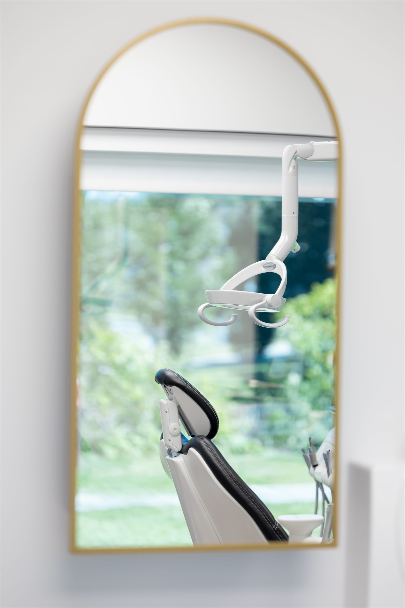 Miroir en arche à cadre doré reflétant une salle de traitement de la clinique de prosthodontie, Québec